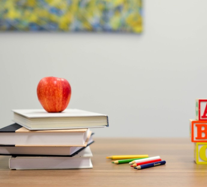 Rødt æble på en bog ved siden af stablede A B C-klodser